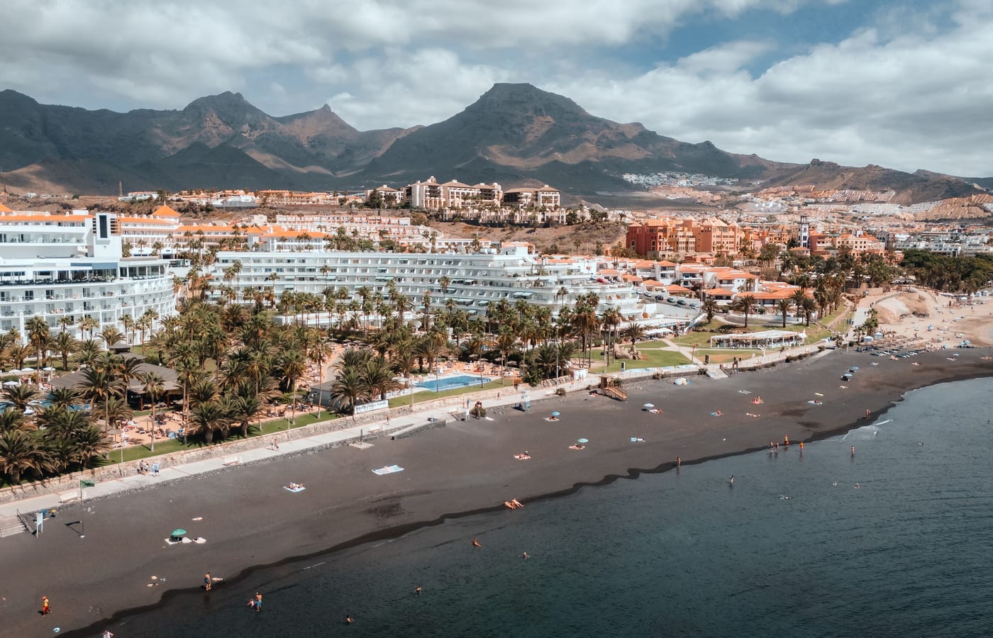 The curve of the beach at Costa Adeje with the hotel front behind it and mountains inland