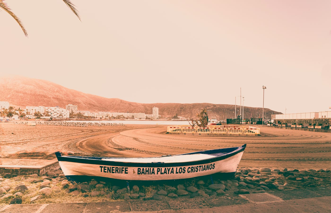 A wooden fishing boat pulled up on the sand at Los Cristianos with the town behind