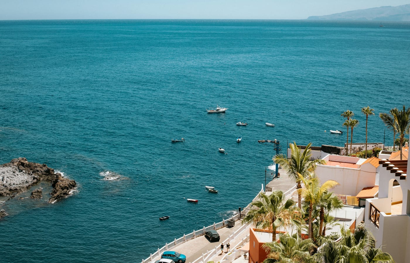 Turquoise water in a small bay at Los Gigantes with white buildings on the point above
