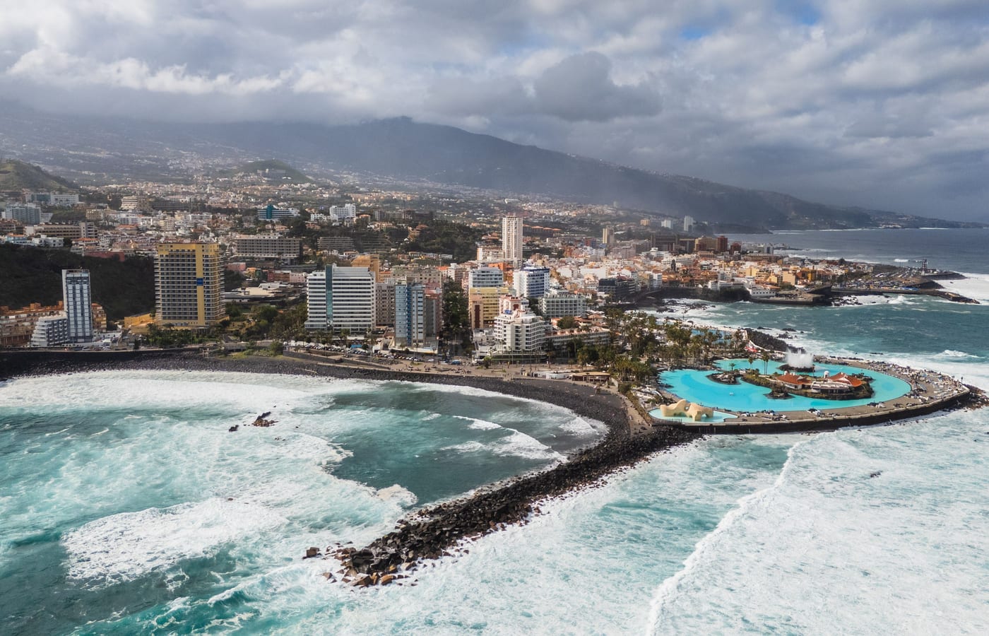 An aerial view of Puerto de la Cruz with its sea pools and the coastline curving away